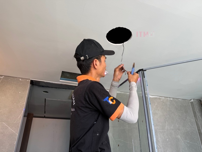 Kỹ thuật viên T&C thao tác với dây nối loa âm trần tại lỗ lắp đặt