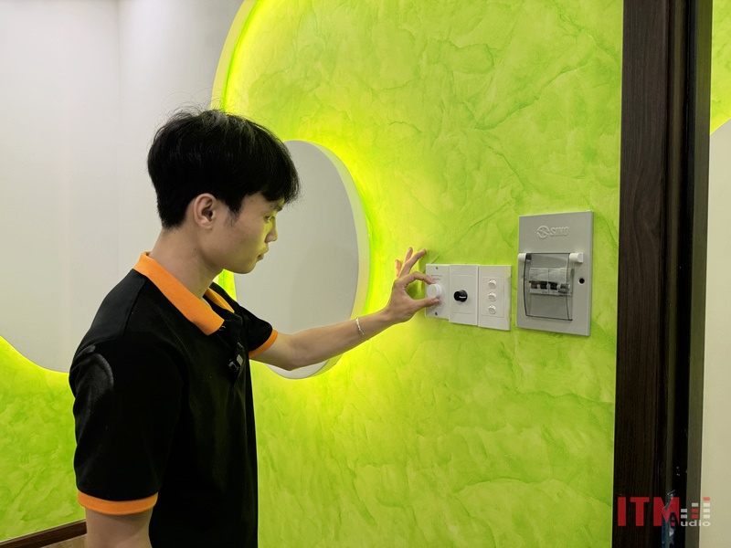 Kỹ thuật viên T&C kiểm tra bộ điều khiển âm thanh trên tường tại spa
