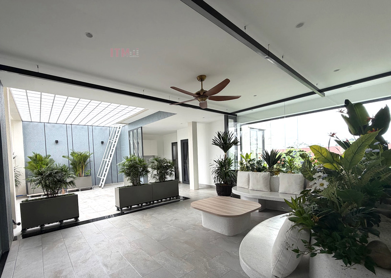 Không gian ngồi thư giãn cạnh sân trong có loa âm trần và cây xanh