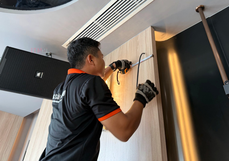 Kỹ thuật viên T&C đo vị trí lắp đặt trong phòng giải trí có loa treo tường